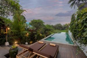 een zwembad met een chaise longue naast een resort bij Ubud Padi Villas in Ubud