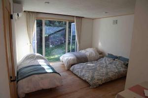 2 camas en una habitación con ventana en 西神楽の杜, en Nishi-kagura