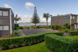 a parking lot in front of a building with bushes at Aqua Soleil Beachfront Apartment in Whitianga