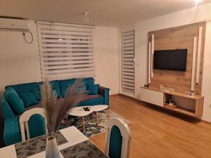 a living room with a blue couch and a tv at Cozy Apartment in Lukavica