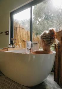 a woman sitting in a bath tub reading a book at Boshuis Farm Stay in George