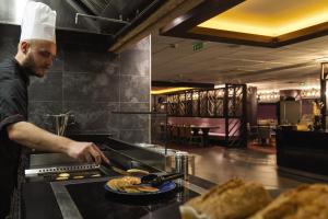 un chef que prepara comida en la cocina del restaurante en Belambra Clubs Tignes Val Claret, en Tignes