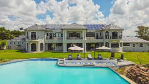 una casa grande con piscina frente a ella en Villa Tasha Luxury Suites, Lanseria, en Johannesburgo
