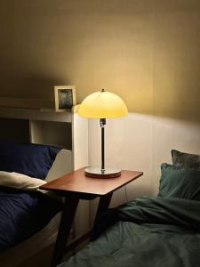 a lamp sitting on a table next to a bed at Vivir Stay Seoul in Seoul