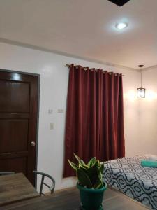 邦勞的住宿－Mannah Garden Staycation Place，一间卧室配有床和红色窗帘