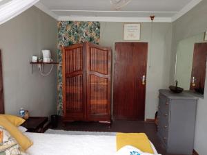 ein Schlafzimmer mit einem Bett, einem Holzschrank und einer Tür in der Unterkunft Campbell Stays in Kestell