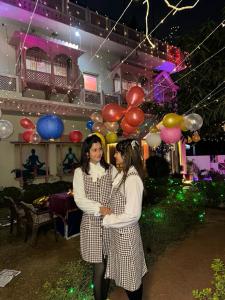 Due donne in piedi l'una accanto all'altra davanti ai palloncini di Hotel Singhasan House a Jaipur