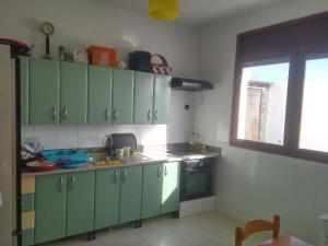 a kitchen with green cabinets and a sink at Villa Alhucemas in Imzoûrene