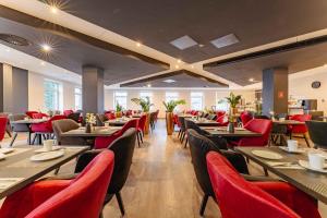a restaurant with tables and chairs and red chairs at Best Western PLAZA Hotel Grevenbroich in Grevenbroich
