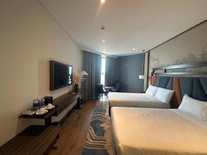 een hotelkamer met 2 bedden en een flatscreen-tv bij Apec Condotel Phan Thiet By Tien Vu in Mũi Né