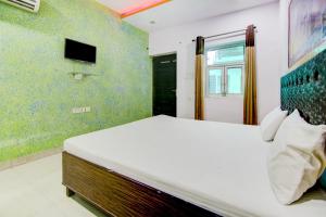 1 dormitorio con 1 cama grande y TV en SPOT ON Relax Inn, en Tājganj