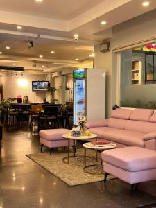 a living room with pink furniture and a restaurant at Paragon Hotel PMH in Ho Chi Minh City
