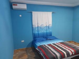 ein blaues Zimmer mit einem Bett und einem Fenster in der Unterkunft Bijilo Villa in Bijilo