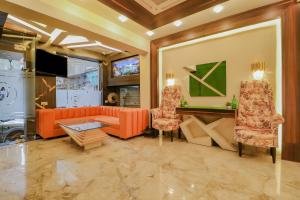 sala de estar con sofá naranja y 2 sillas en Capital O Western Galaxy, en Amritsar