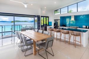 cocina y comedor con mesa de madera y sillas en Edge Penthouse on Hamilton Island by HIHA en Isla Hamilton