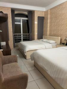 una habitación de hotel con 2 camas y una silla en Căn hộ Sao Mai - Nội Bài Hà Nội, en Hanói