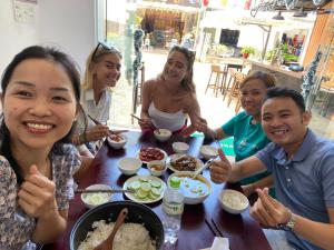 a group of people sitting around a table eating food at Dom Hostel and Bar in Hoi An