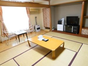 a living room with a coffee table and a tv at Ryokan HANAEMI in Otaru