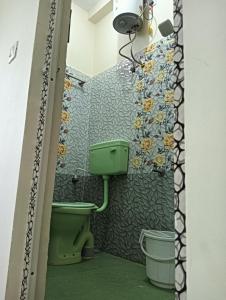 La salle de bains est pourvue de toilettes vertes et de fleurs sur le mur. dans l'établissement Rose Villa Pondicherry, à Pondichéry