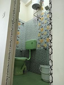 a bathroom with a green toilet and flowers on the wall at Rose Villa Pondicherry in Puducherry