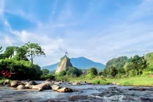 a river with rocks and a mountain in the background at Exorcism Camp in Bukittinggi