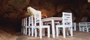 un grupo de sillas blancas sentadas alrededor de una mesa en Cave Diani Holiday Apartments en Diani Beach