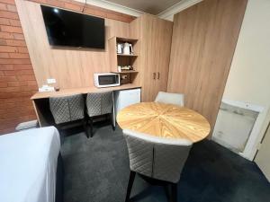 a room with a table and chairs and a tv at Adrian Motel in Forbes
