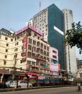 a tall building with signs on it in a city at Hotel In Need - Near to the US and Canada Embassy in Dhaka in Dhaka