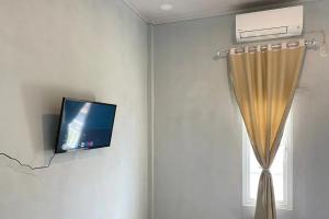 a room with a tv and a curtain and a window at RedDoorz Syariah near Kantor Bupati Pantai Pandan Sibolga in Halangan