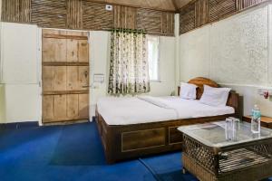 a bedroom with a bed and a table and a door at OYO Dooars Green Resort in Chālsa Mahābāri