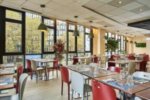 un restaurante con mesas, sillas y ventanas en Campanile Paris Sud - Porte d'Orléans - Arcueil, en Arcueil