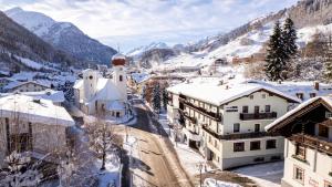 a town covered in snow with mountains in the background at Hotel Pension Kirchplatz in Sankt Anton am Arlberg