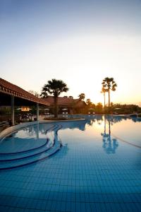 a large swimming pool with a sunset in the background at Angkor Palace Suite & Villa in Siem Reap