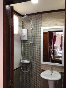 a bathroom with a sink and a shower and a mirror at Granny One Guest House in Chiang Khan