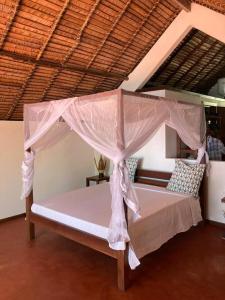 uma cama de dossel num quarto em Villa Colibri em Nosy-Be