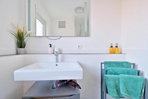 La salle de bains est pourvue d'un lavabo blanc et de serviettes vertes. dans l'établissement Exklusiv & Zentral: 1-Zi. Apartment mit Balkon Stellplatz, à Bayreuth