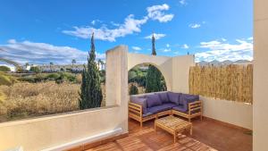 une terrasse avec un canapé violet et une clôture dans l'établissement Garden vistas. Hermoso dúplex con patio, solárium y piscina., à Vera