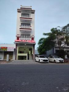 dos autos blancos estacionados frente a un edificio en Khách sạn Gia Nghiêm 2, en Ấp Cái Giá