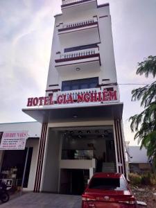 um edifício de hotel com um carro vermelho estacionado em frente em Khách sạn Gia Nghiêm 2 em Ấp Cái Giá
