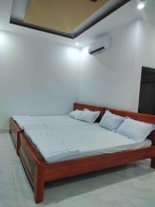 uma cama de madeira num quarto com uma parede branca em Khách sạn Gia Nghiêm 2 em Ấp Cái Giá