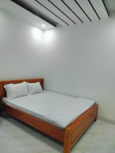 uma cama num quarto com uma parede branca em Khách sạn Gia Nghiêm 2 em Ấp Cái Giá