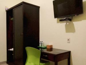 a room with a desk and a tv and a green chair at RedDoorz near Pantai Pandan Sibolga 2 in Halangan