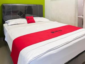 a large bed with a red blanket on it at RedDoorz near Pantai Pandan Sibolga 2 in Halangan +3 photos