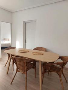 Apartamento 12 de Octubre, Almendrales في مدريد: طاولة خشبية مع كراسي وسرير في الغرفة