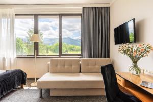 a hotel room with a couch and a desk and window at Hotel Helios in Zakopane