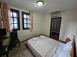 a bedroom with a bed and a desk and windows at Вилна Къща Кедър in Dolna Banya