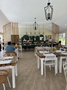 un restaurant avec des tables et des chaises et des personnes en arrière-plan dans l'établissement The Eliana Farm Resort and Villas, à Manolo Fortich