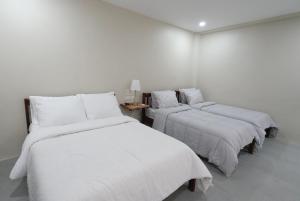 - 3 lits dans une chambre aux murs blancs dans l'établissement The Eliana Farm Resort and Villas, à Manolo Fortich