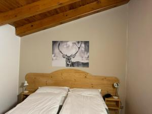 a bedroom with a bed with a deer picture on the wall at Life Hotels Des Alpes in Folgaria
