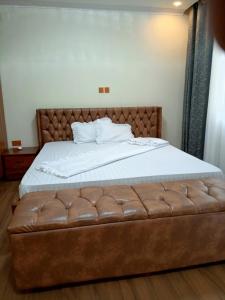 a bed with a brown leather tufted foot board at Kigali Nice Apartment in Kigali